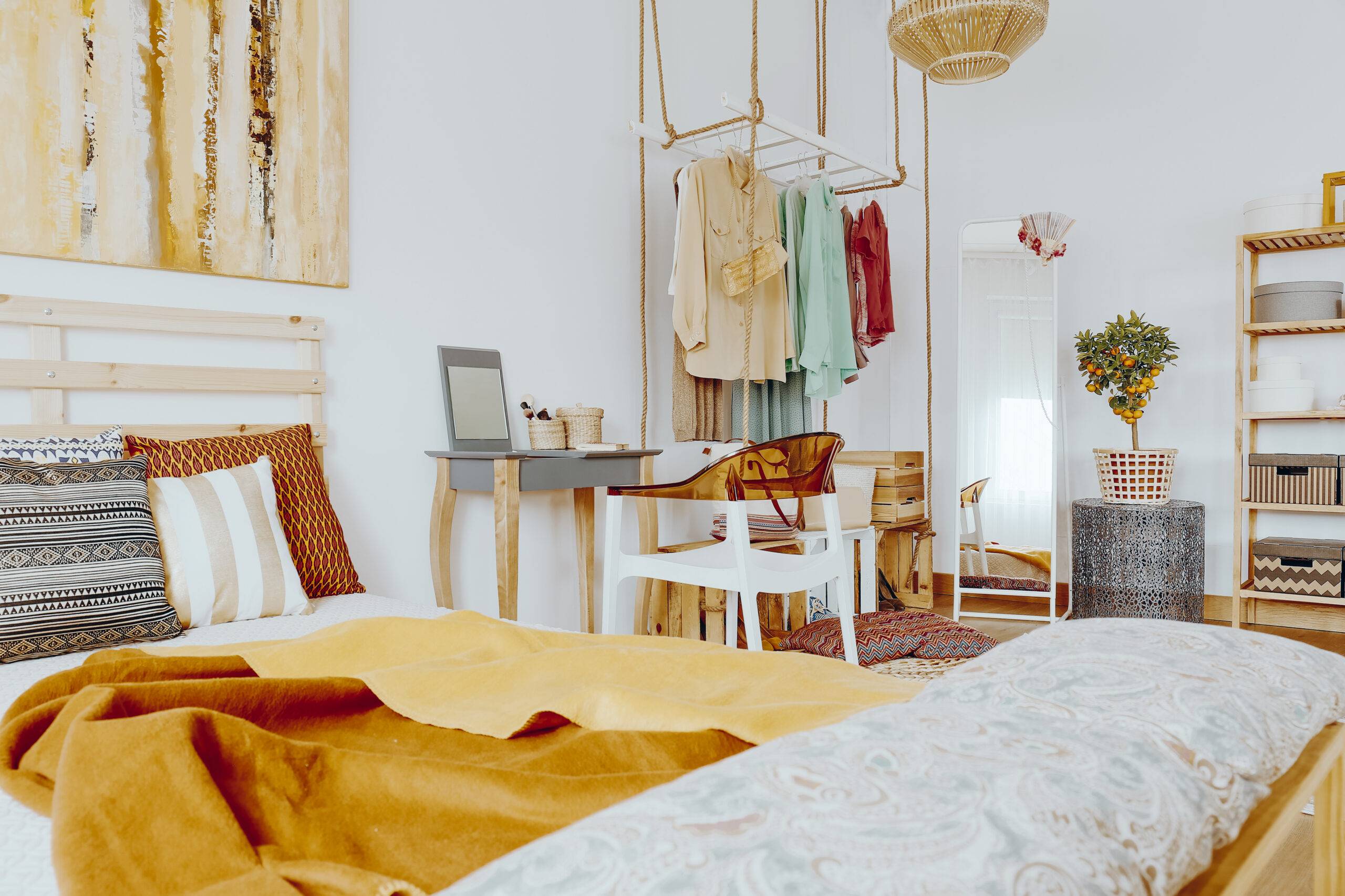 Wooden king-size bed with decorative pillows and blanket in sandy colors