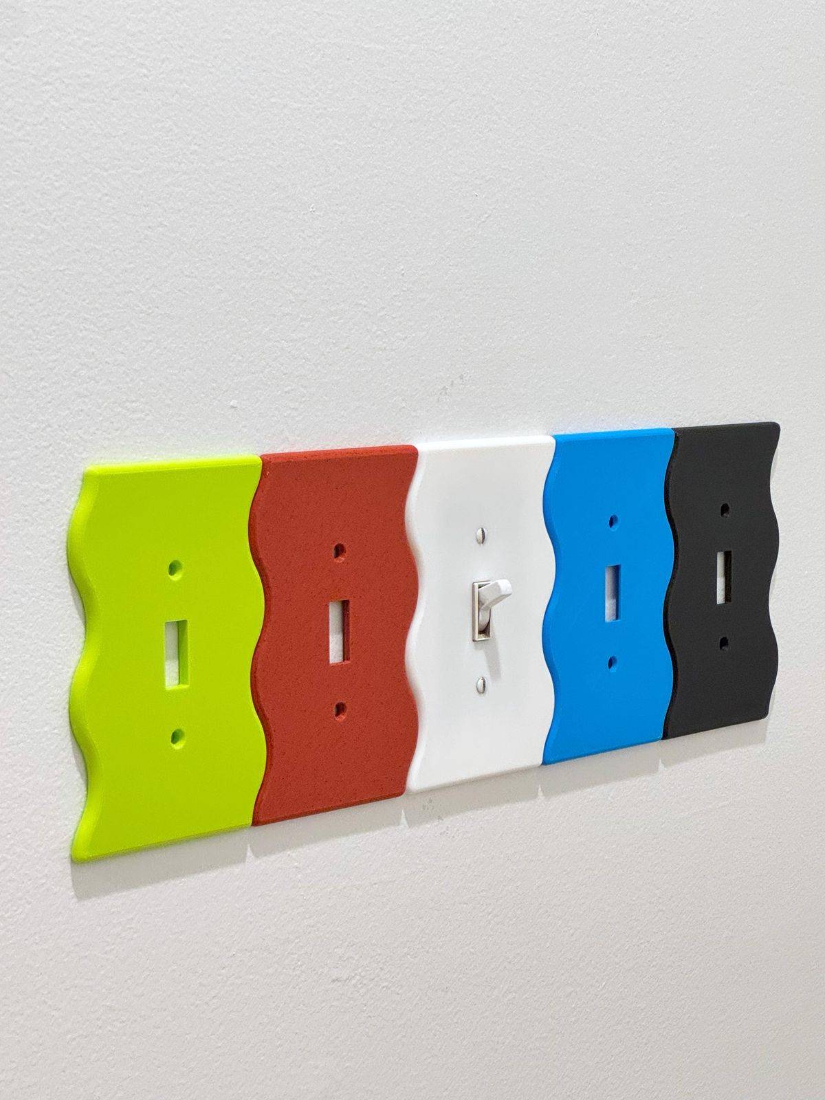 Five wavy light switch covers all lined up next to one another on the wall.