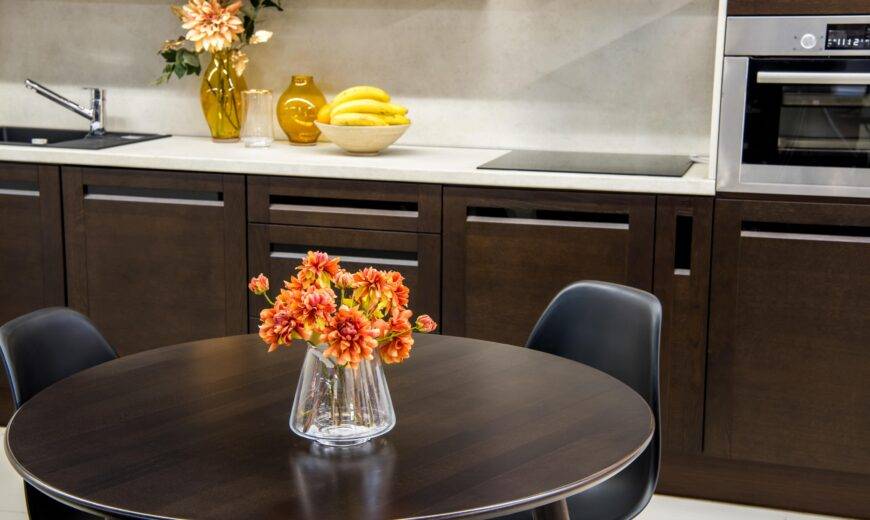 A modern kitchen with dark wood cabinets and dining table.