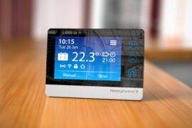 A smart digital thermostat sitting on a counter.