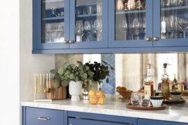 Blue glass-front cabinets holding largely glassware with a white countertop.