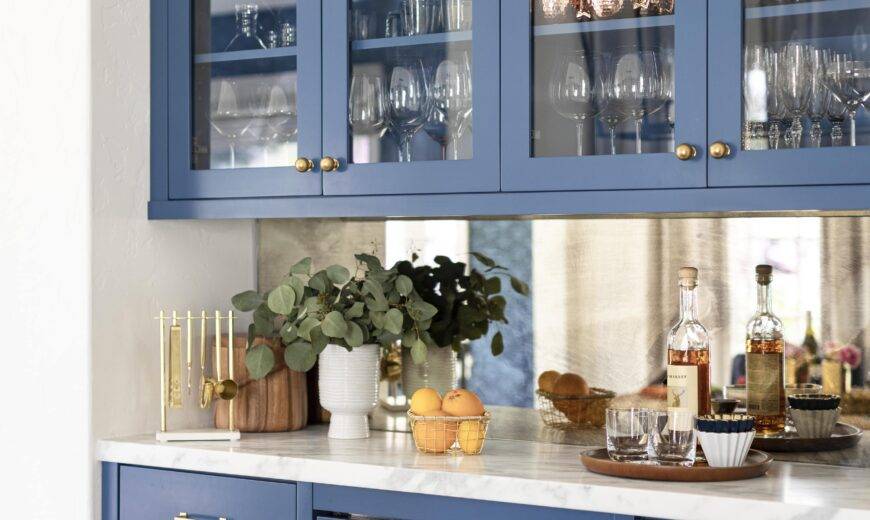 Blue glass-front cabinets holding largely glassware with a white countertop.