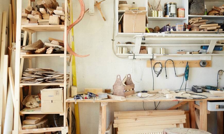 Workbench of carpenter with assortment of wooden workpieces, toolbox and other equipment
