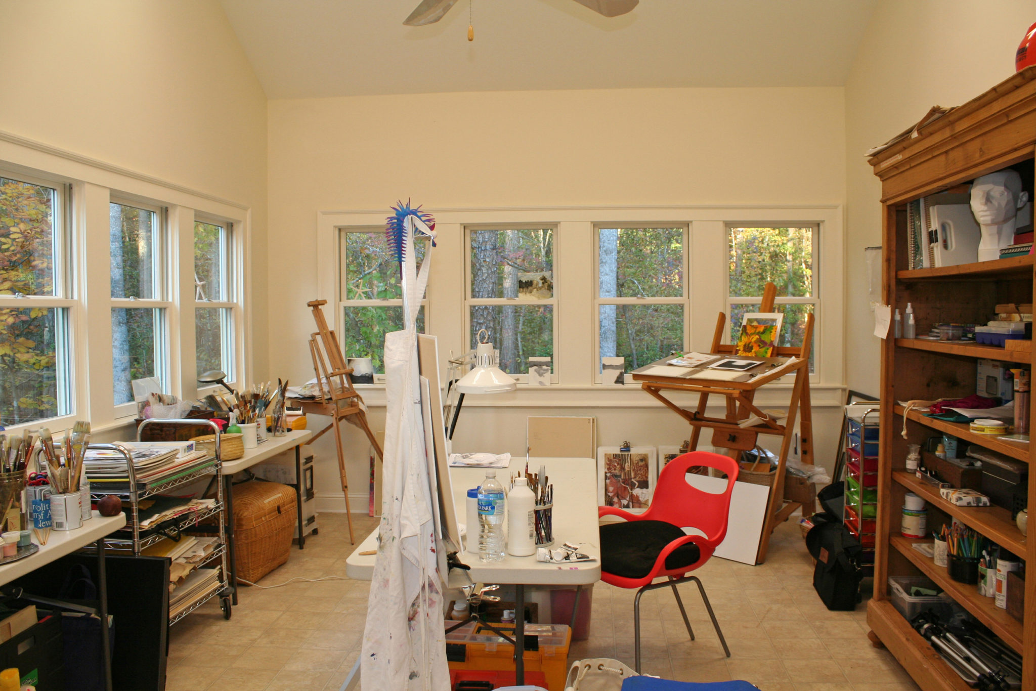 A small art studio with white walls and pink chair.