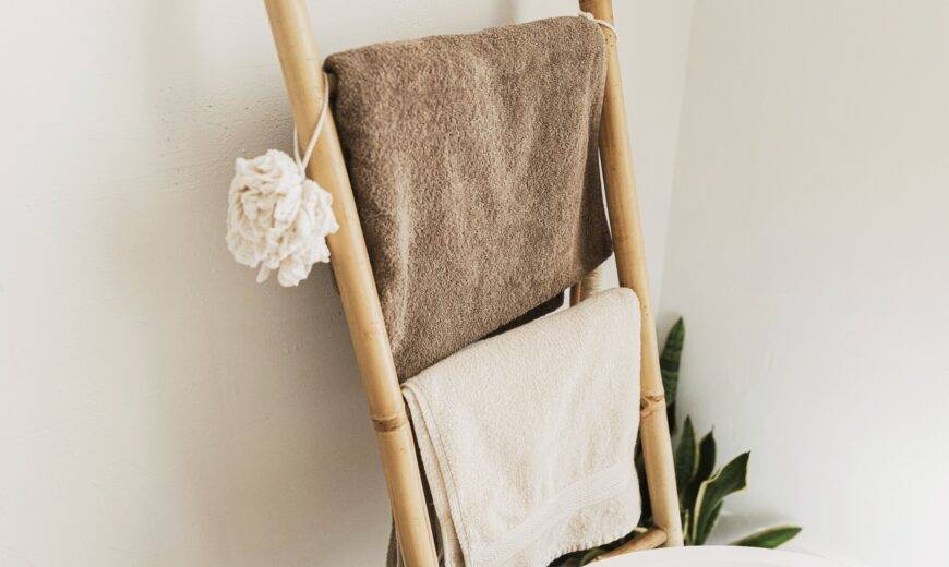 A bamboo towel ladder against a bathroom wall, holding towels.