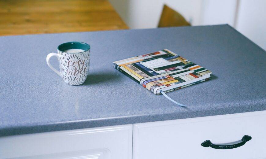 A kitchen counter with a mug and journal on it.