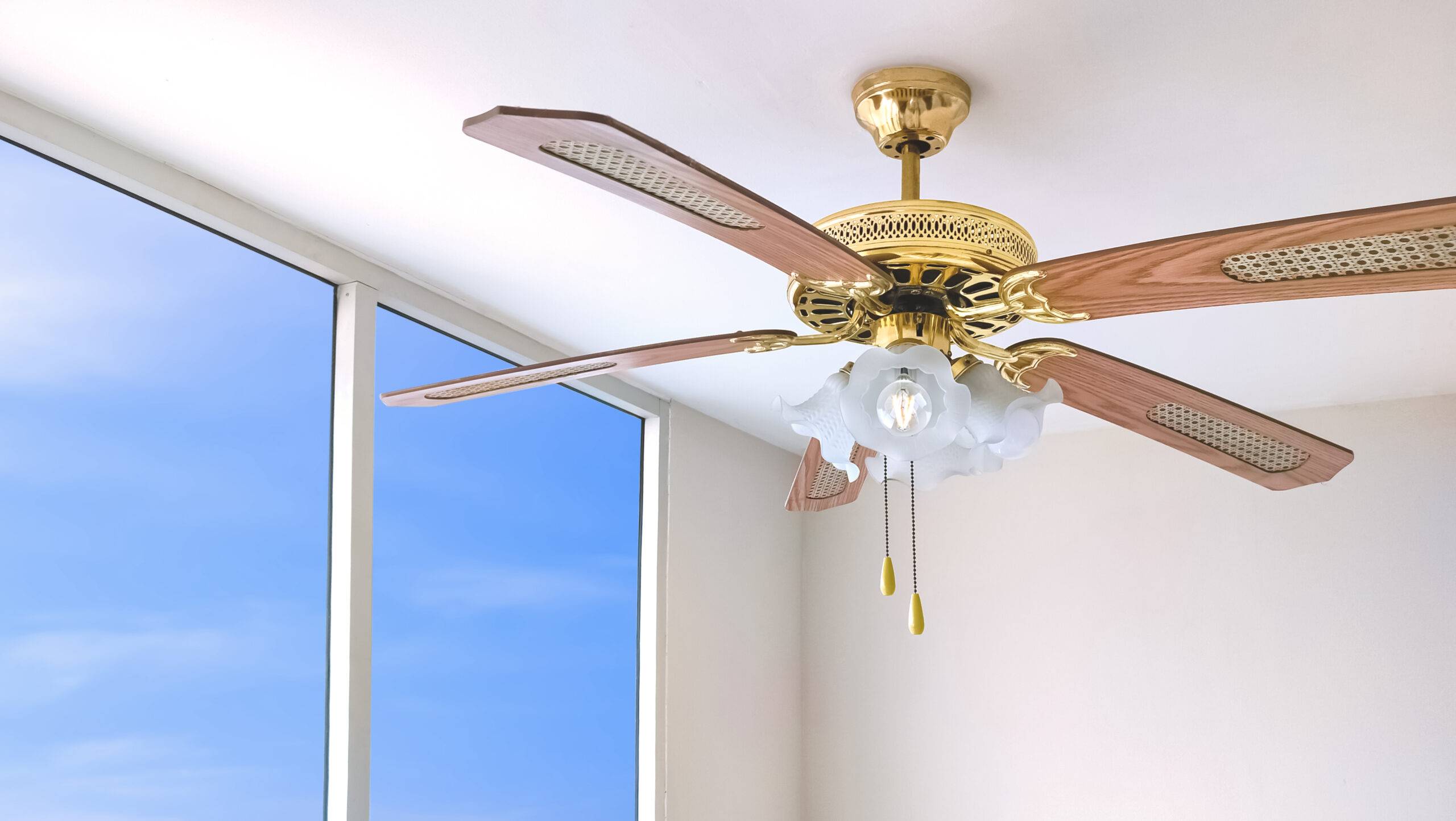 A ceiling fan next to large, sunny balcony doors.