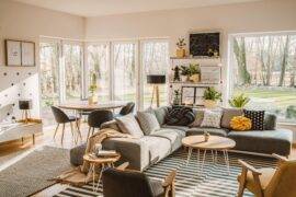 A large, modern living room featuring an L couch and dining table behind it.