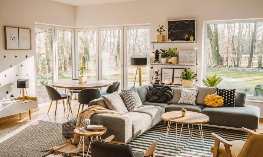 A large, modern living room featuring an L couch and dining table behind it.