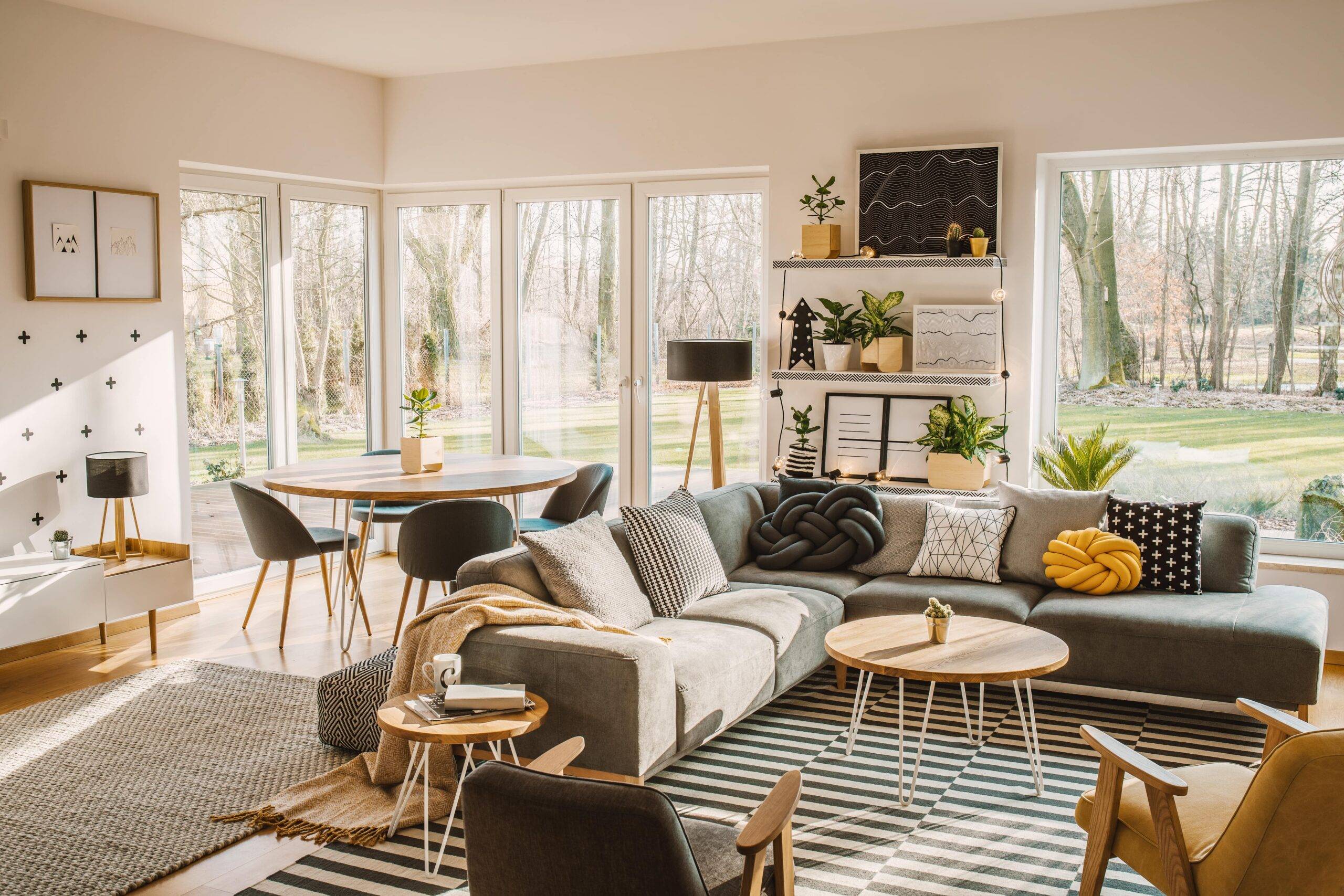 A large, modern living room featuring an L couch and dining table behind it.