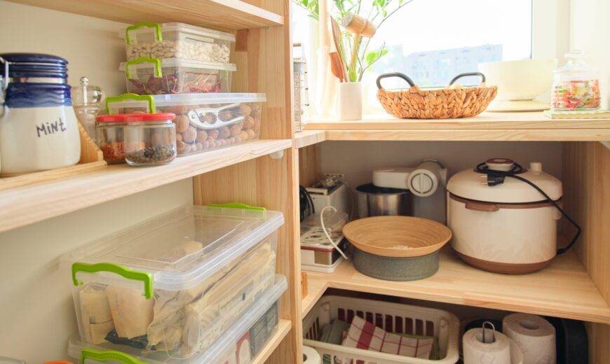 Wooden shelves with food and utensils, kitchen appliances in the pantry.