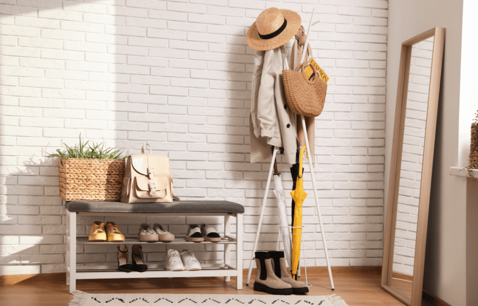 An entryway with a full coat rack and shoe rack next to it.